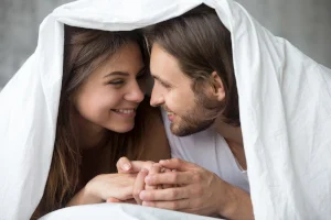 Чоловік та жінка всміхаються один одному в ліжку